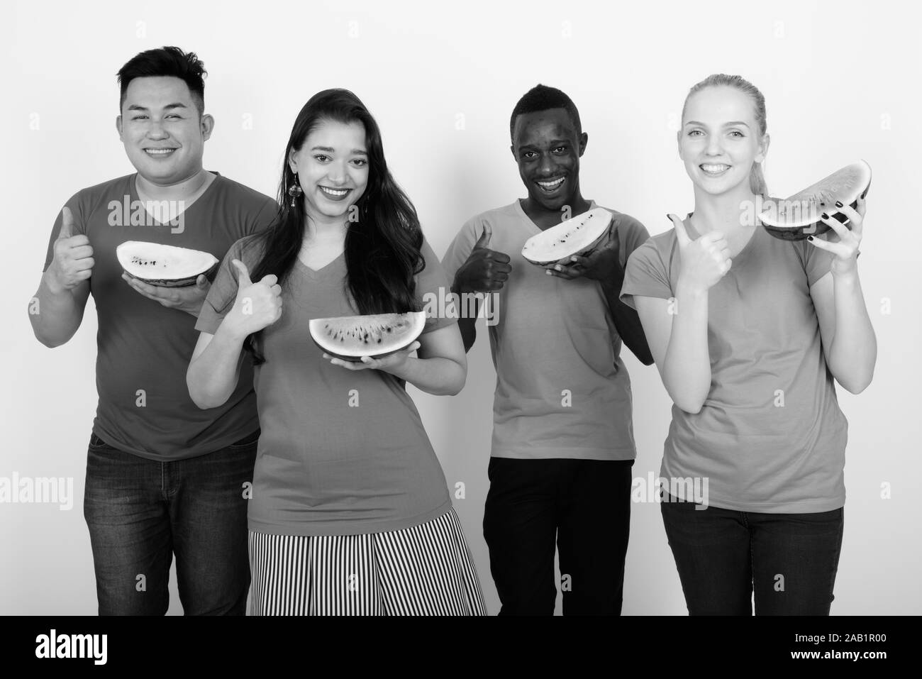 Studio shot of happy diverse group of multi ethnic friends smiling while holding slice of watermelon and giving thumb up together Stock Photo