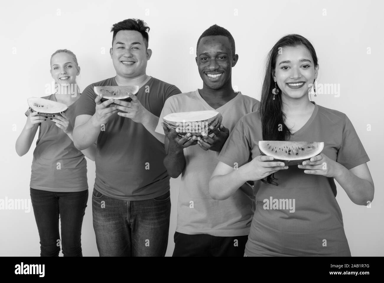 Happy young Indian woman with diverse group of multi ethnic friends holding slice of watermelon and lining together Stock Photo