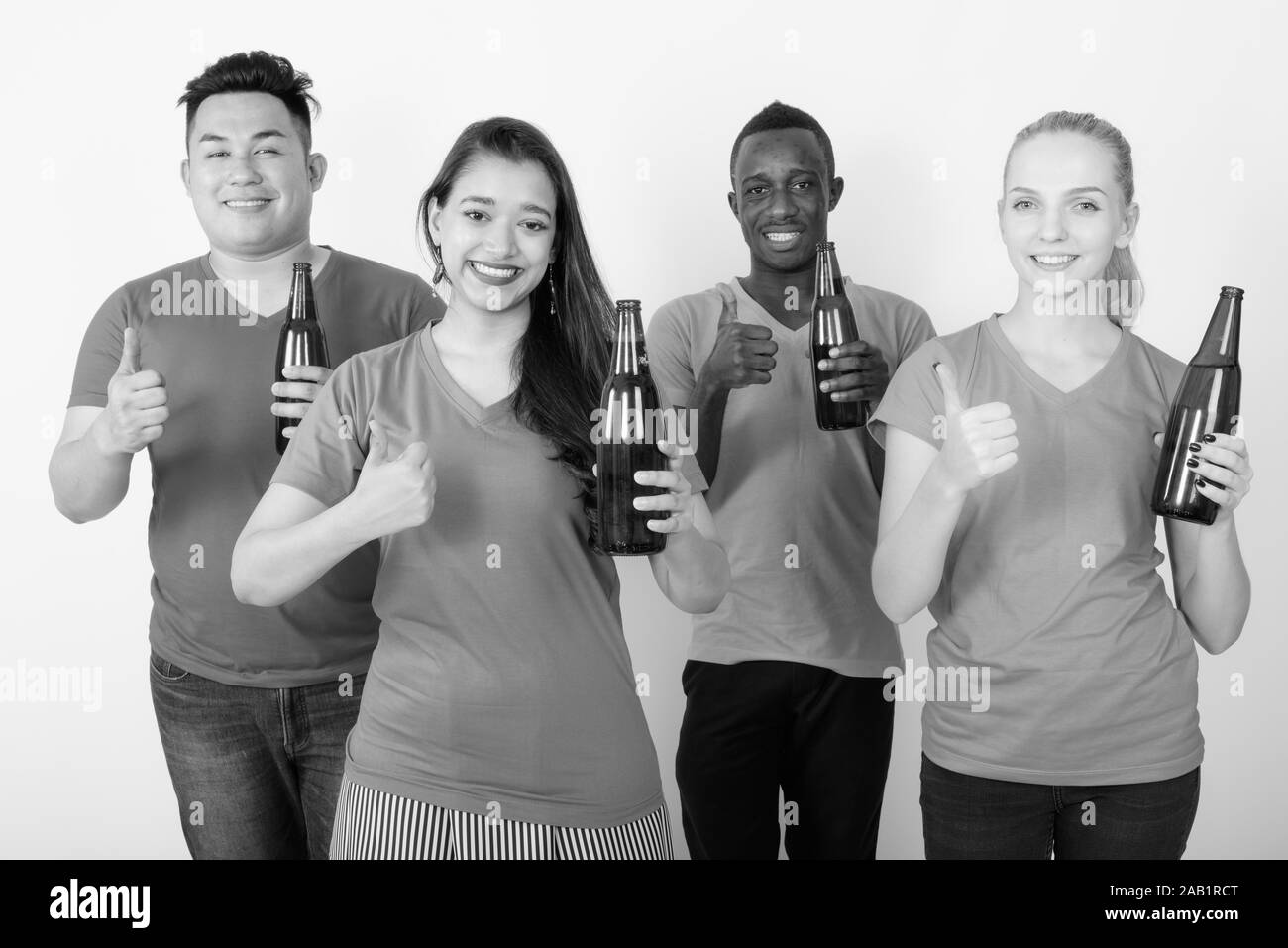 Studio shot of happy diverse group of multi ethnic friends smiling while holding bottle of beer and giving thumb up together Stock Photo