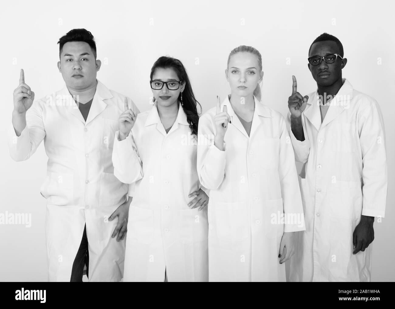 Studio shot of diverse group of multi ethnic doctors pointing finger up together Stock Photo