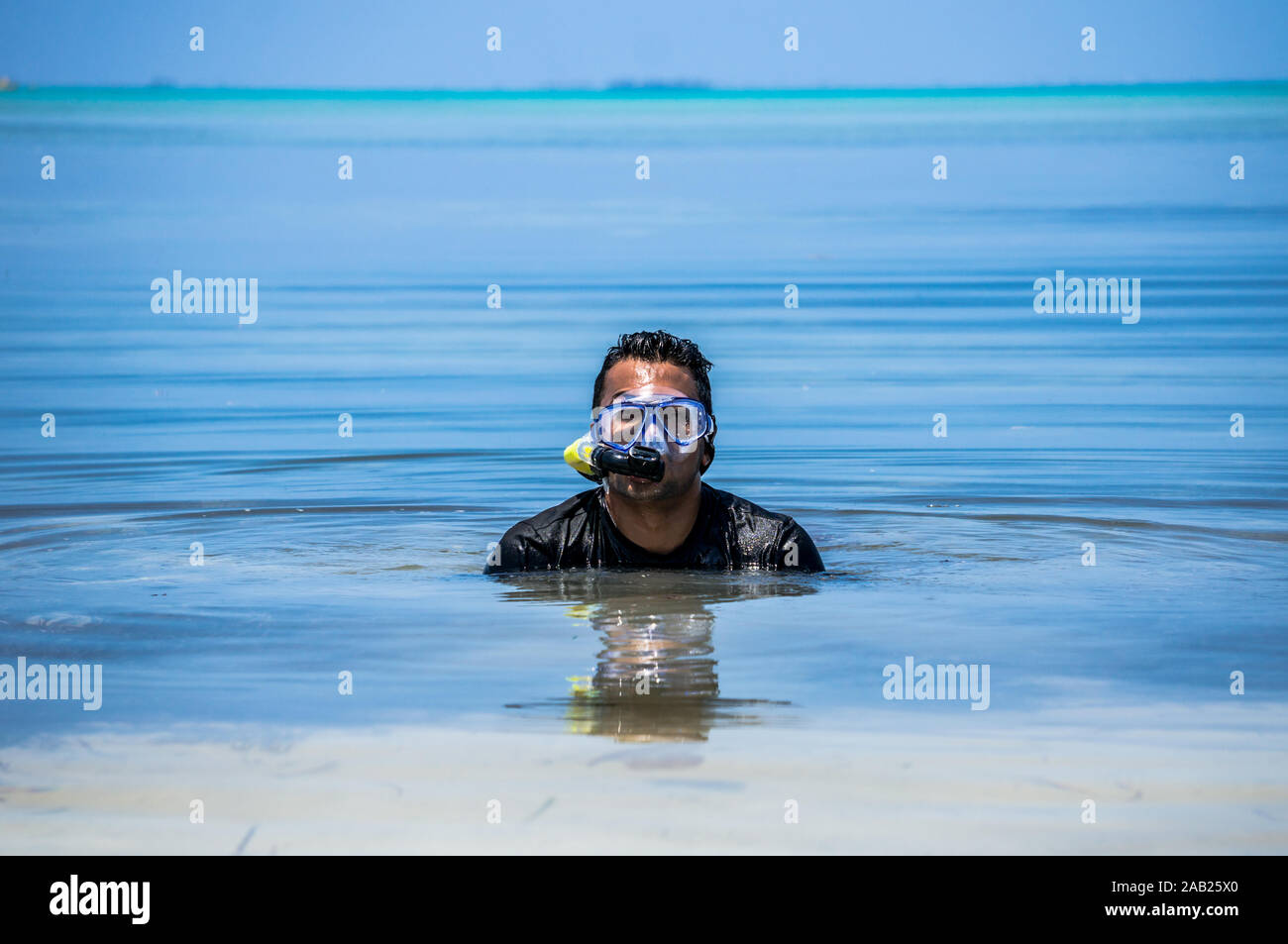 Indian man with snorkeling equipment in ocean water in the Maldives Stock Photo