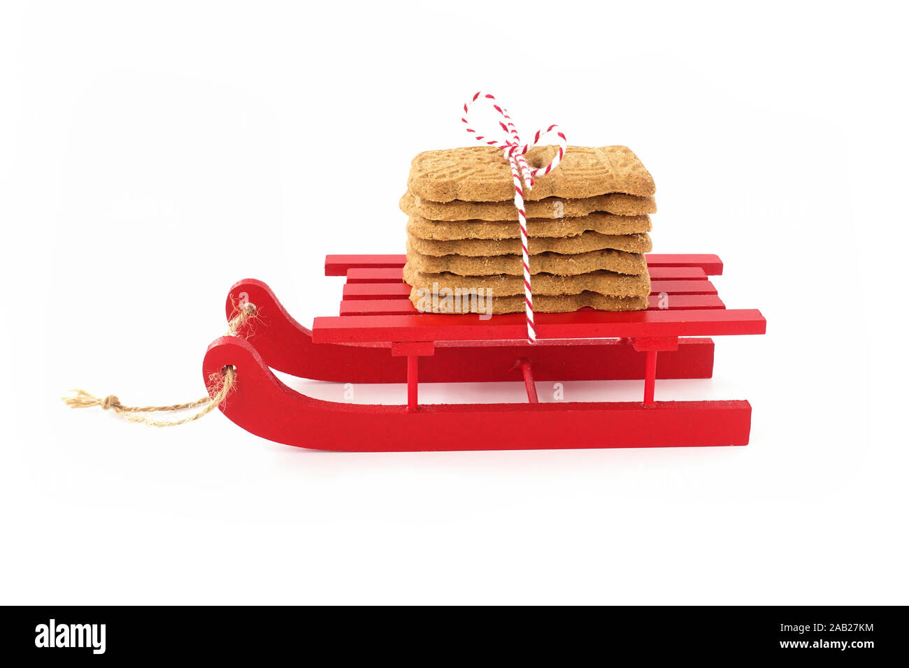 Spekulatius, Speculaas, Speculoos, spiced Christmas cookies on red wooden sledge isolated on white. Low Angle view. Stock Photo
