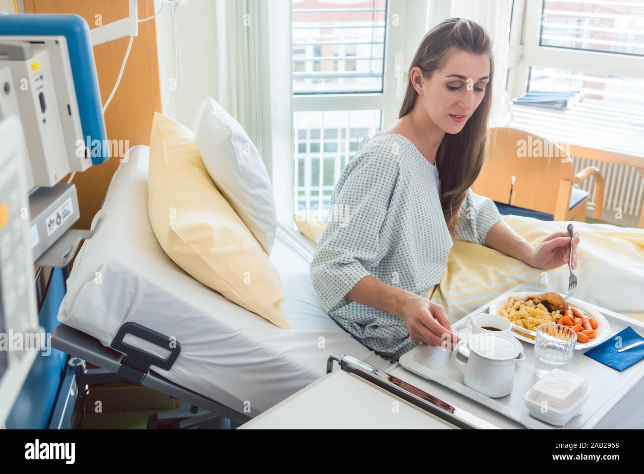 Patient in hospital lying in bed eating meal Stock Photo