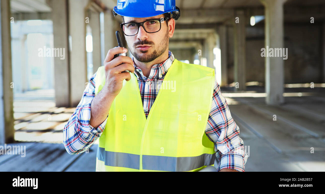 Male architect with blueprints using walkie-talkie Stock Photo