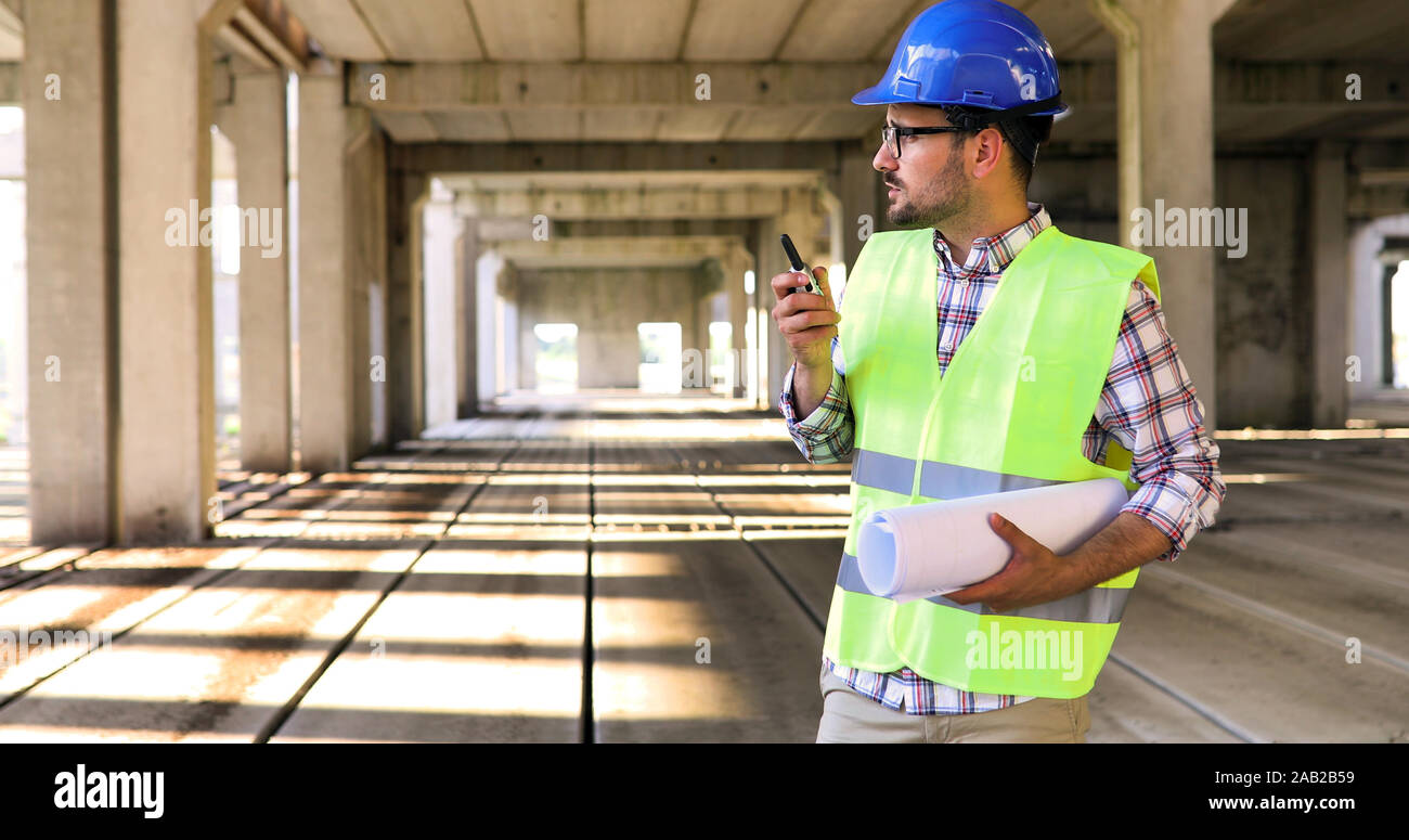 Male architect with blueprints using walkie-talkie Stock Photo
