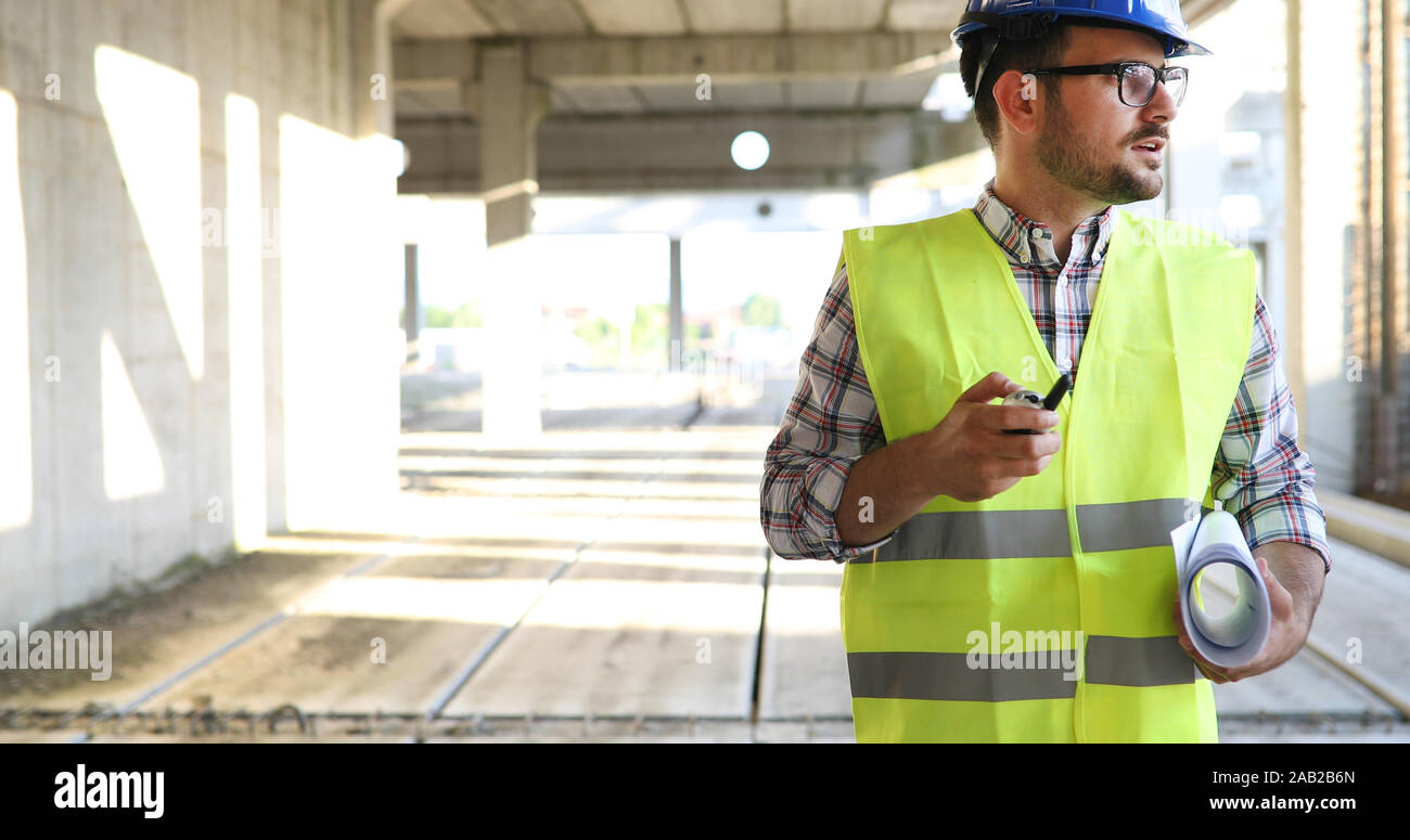 Architect holding rolled up blueprints at construction site Stock Photo