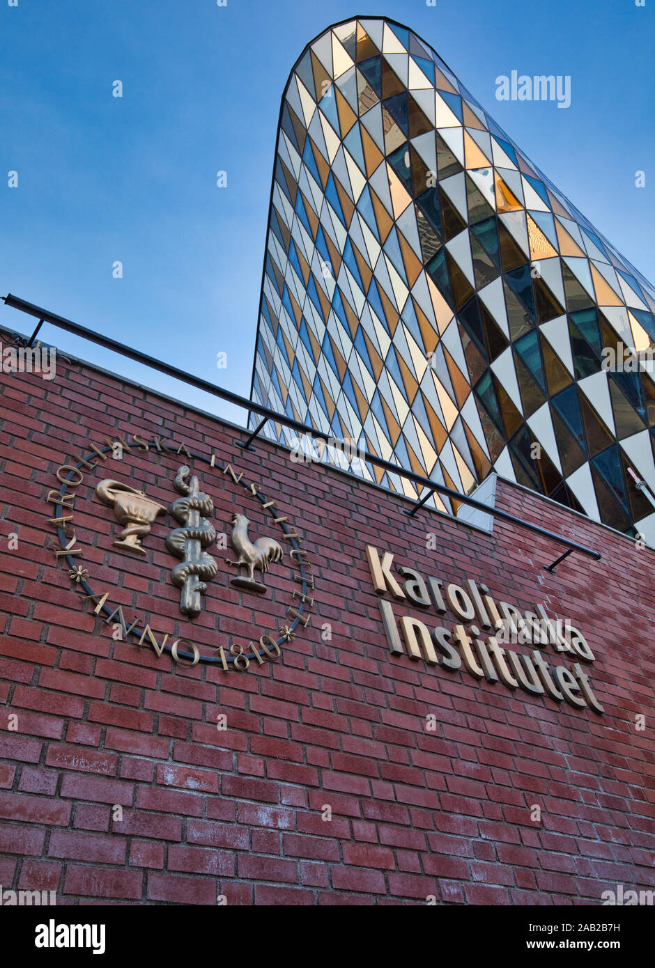 Karolinska Institute (Karolinska Institutet) sign and logo on wall with the Aula Medica glass auditorium behind, Solna, Stockholm, Sweden Stock Photo