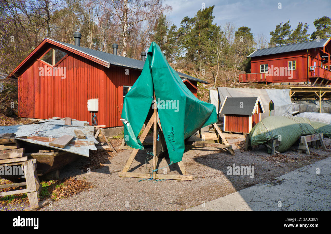 Boat on wooden boat stands covered with tarpaulin and traditional falu ...