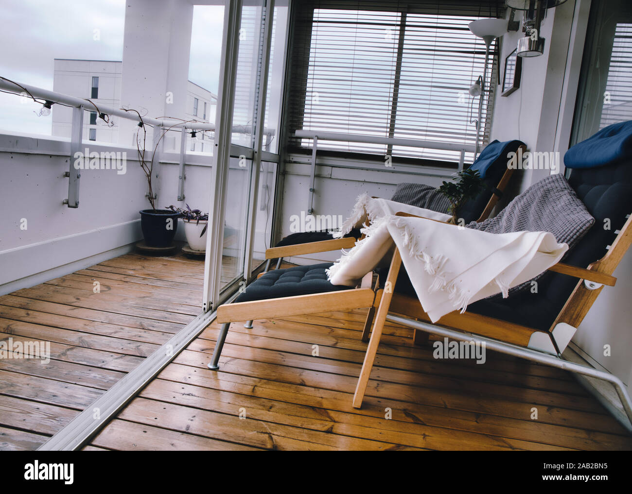 Stylish highrise luxury apartment roof terrace with wooden decking, reclining chairs and glass sliding doors, Upplands Vasby, Stockholm, Sweden Stock Photo