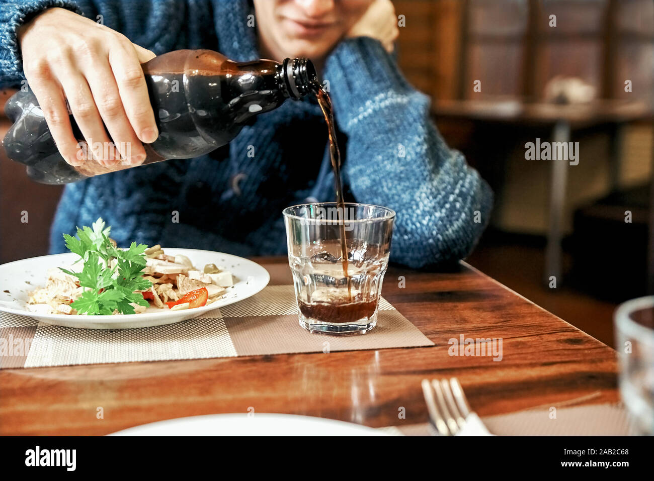 man pours a drink in a glass cup. young guy drinks and eat in a cafe