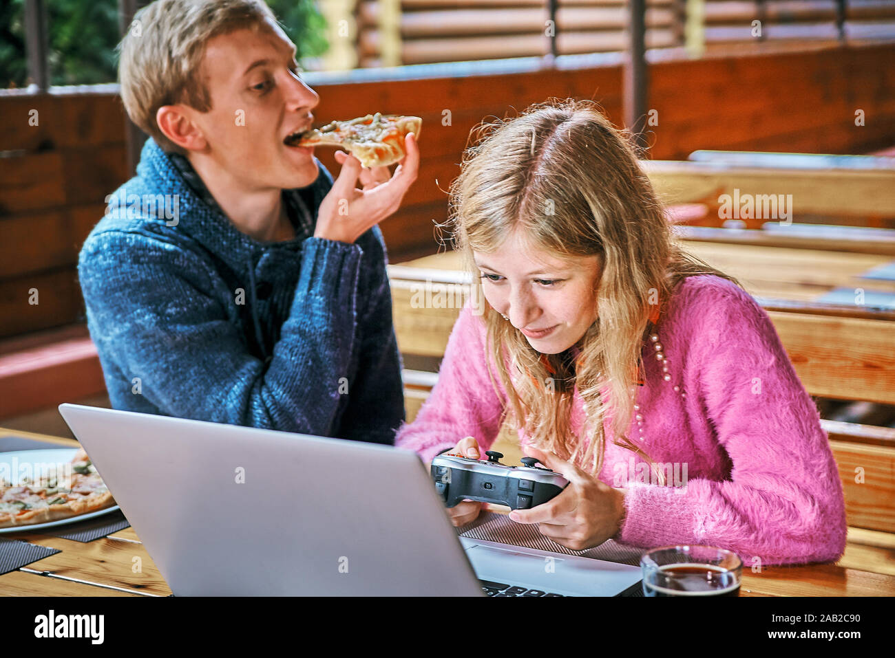 girl gamer in a cafe with a young guy. man eating pizza Stock Photo
