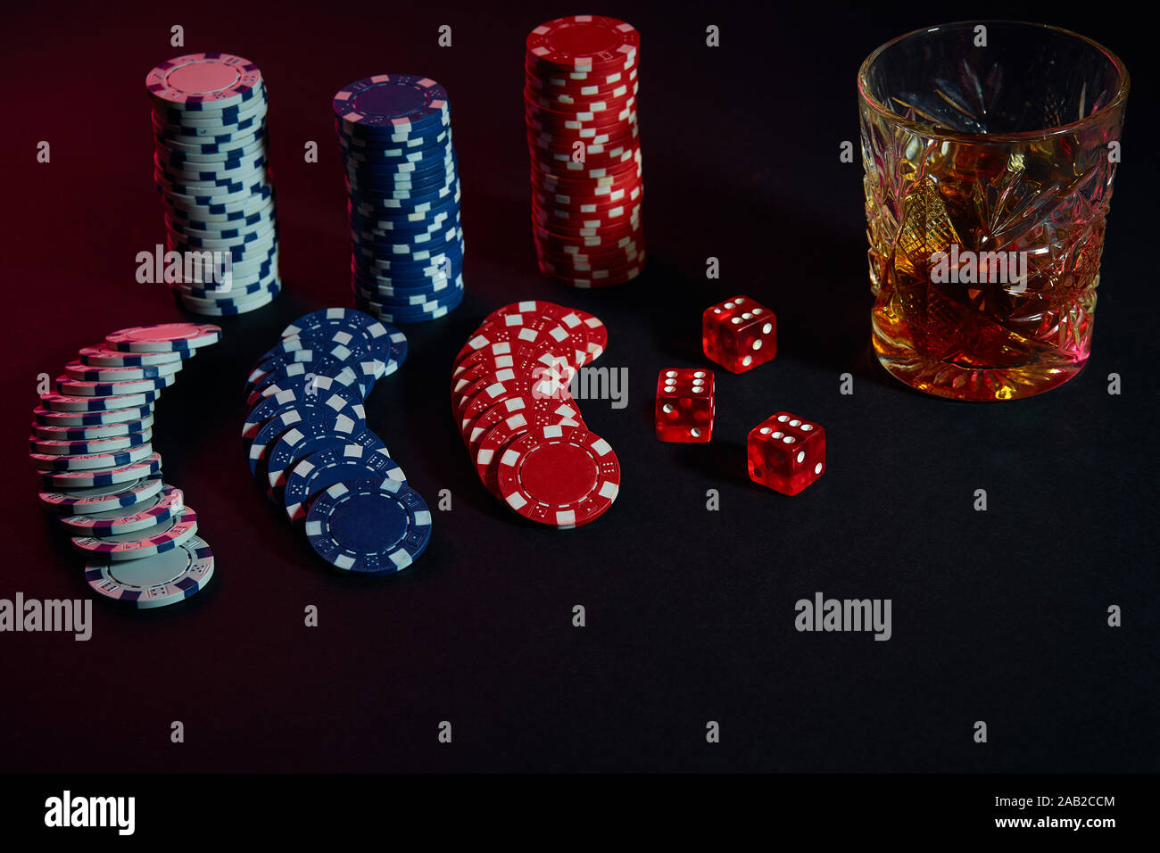 Poker chips and wine glass of cognac on dark table. Gambling Stock