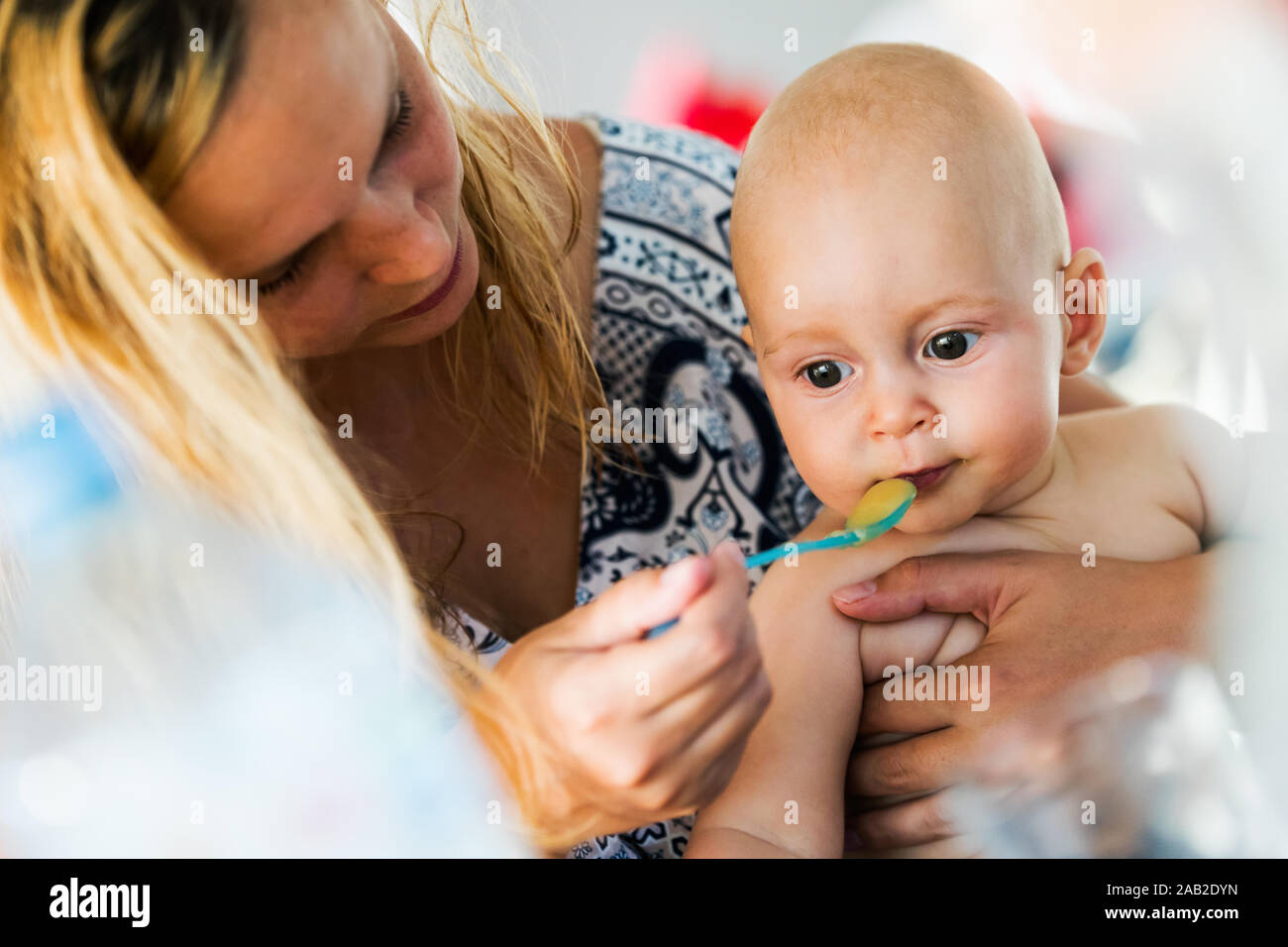 Portrait of mother feeding her baby with spoon Stock Photo