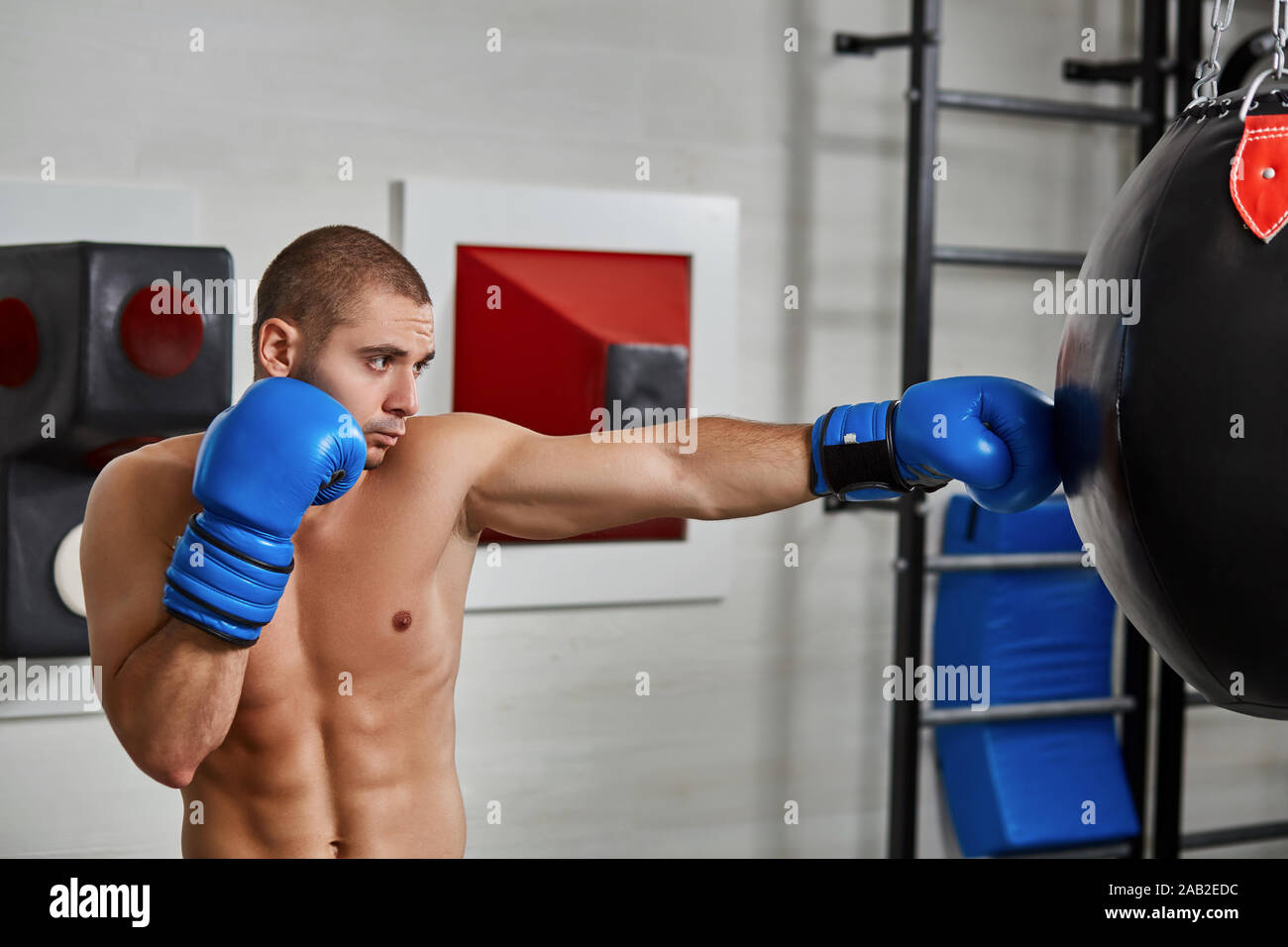 boxer man during boxing hitting heavy bag at training fitness gym Stock