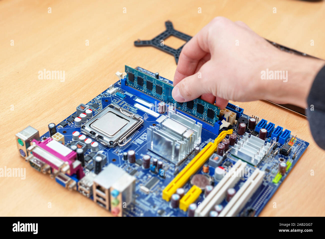 Installing DDR memory on motherboard. Hand pushes the module into the slot provided on the system board. Stock Photo