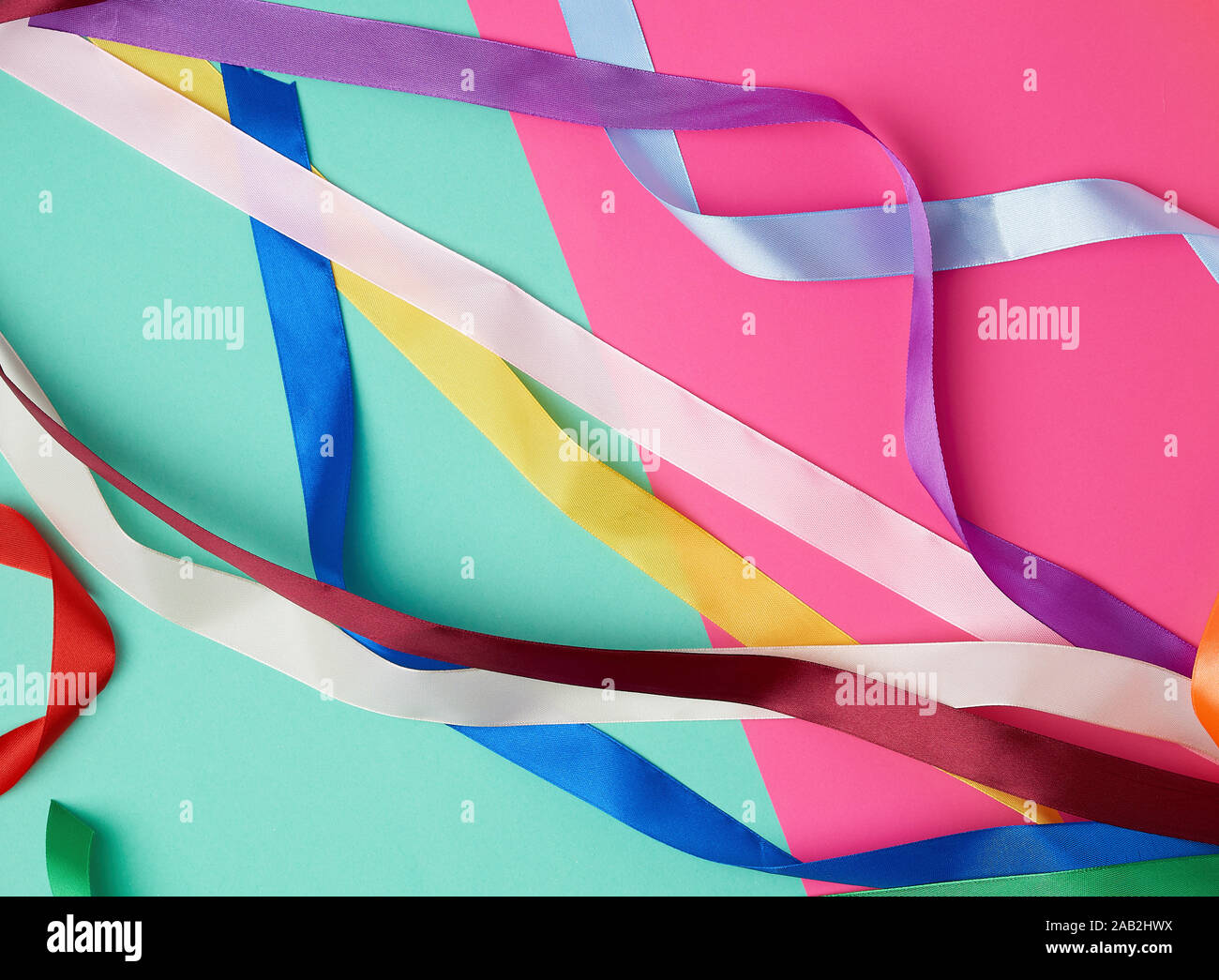 many silk multi-colored ribbons on a colored background, top view Stock Photo