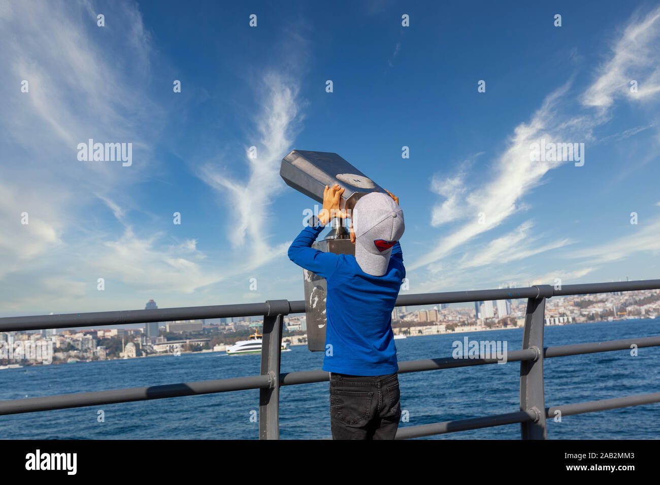 Istanbul, Turkey-Nov.20, 2019: Young boy use street binocular in the coastline of Uskudar district and observe the sky on a sunny day. Stock Photo