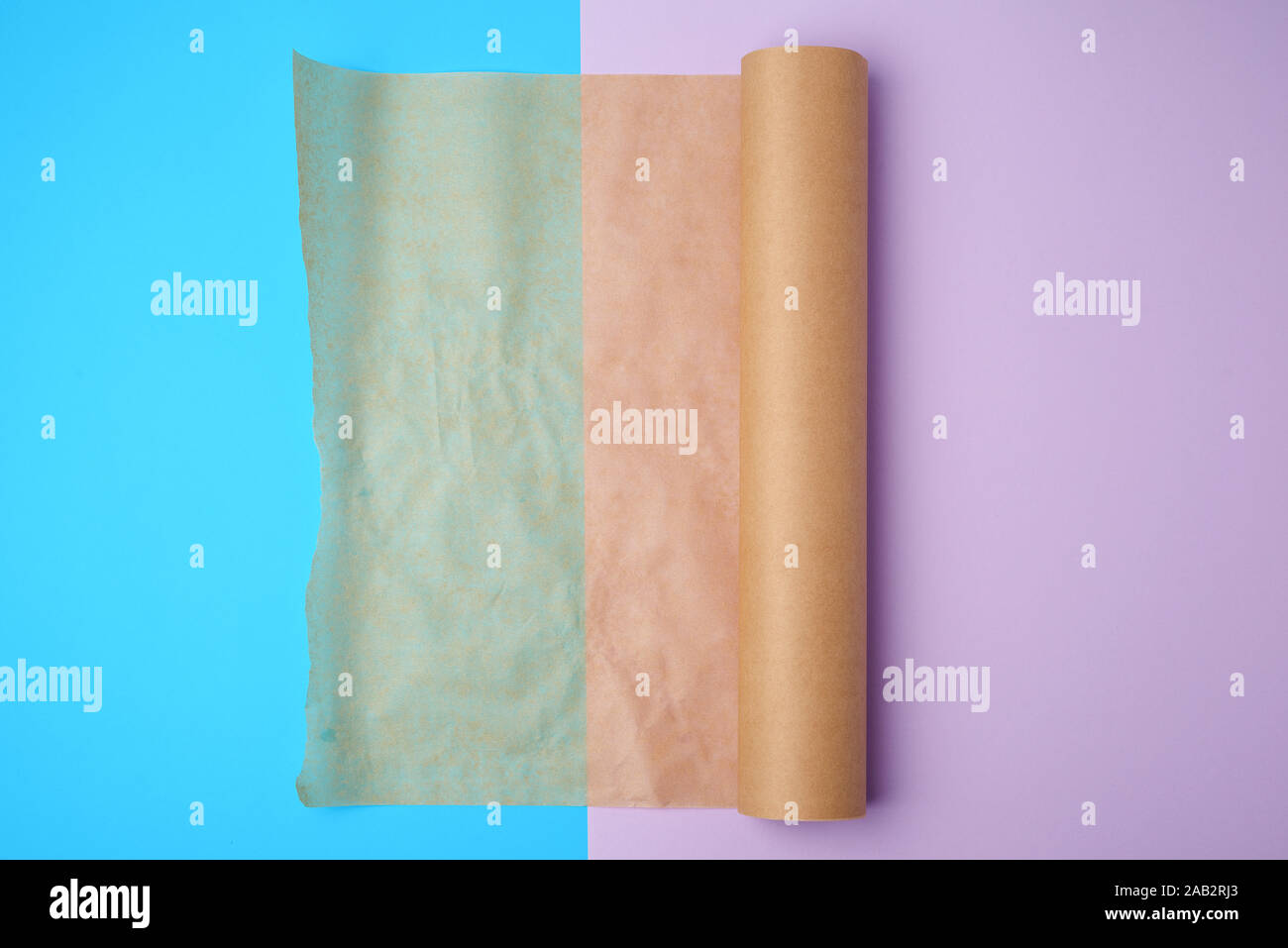 unwrapped a roll of brown parchment paper on a colored background, place for text Stock Photo