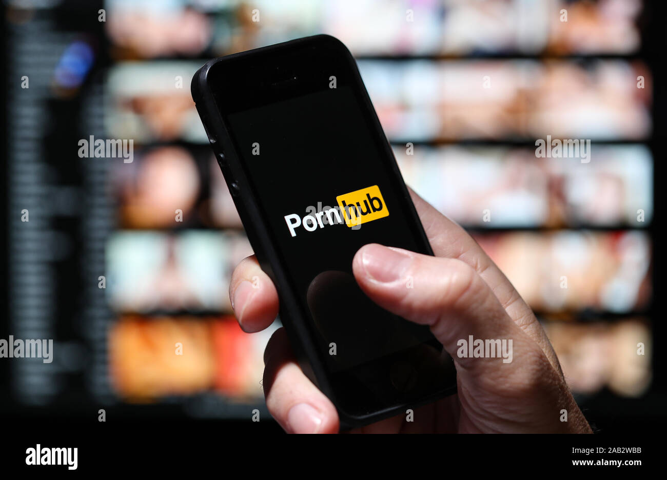A man looking at the Pornhub.com website logo on his phone with the pornhub  website on a computer out of focus in the background Stock Photo - Alamy