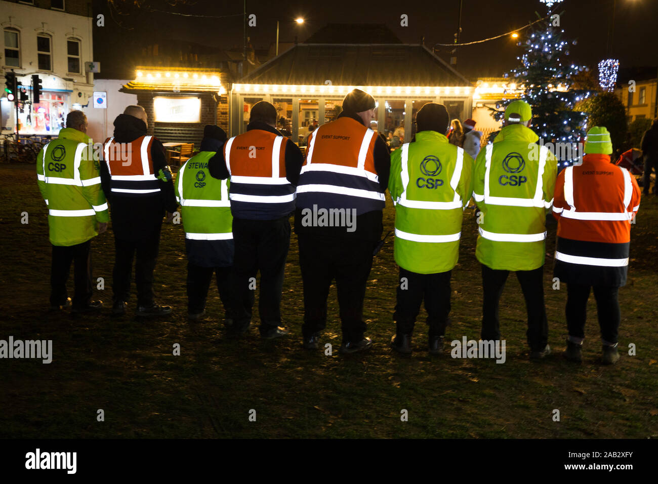 Event stewards in orange, yellow jacket / green hi vis / high visibility jackets with highly reflective stripes / material strips. UK (114) Stock Photo