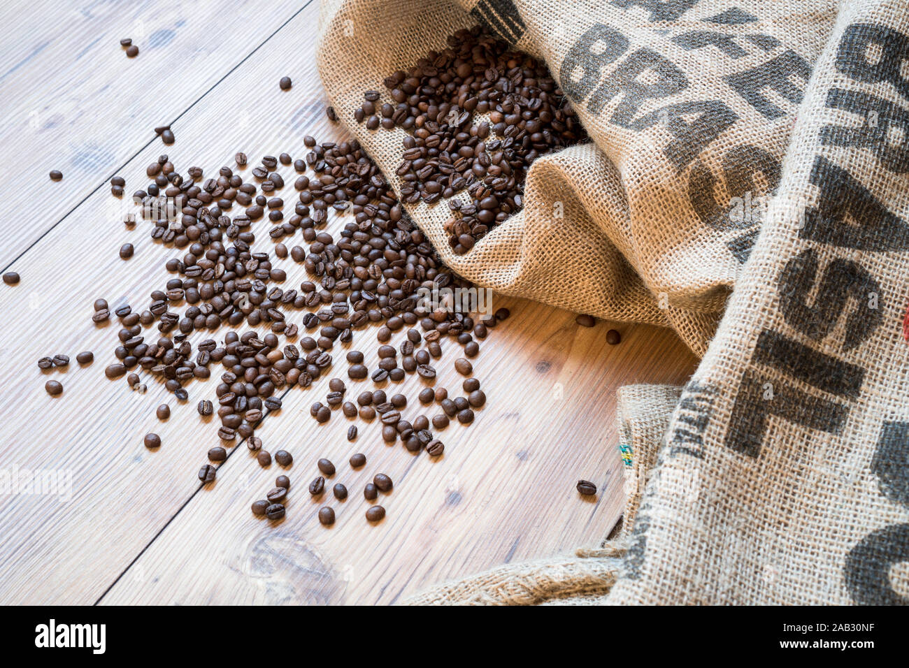 Coffee beans on jute sack and printed Brasil on wooden floor background. Bag of coffee Stock Photo