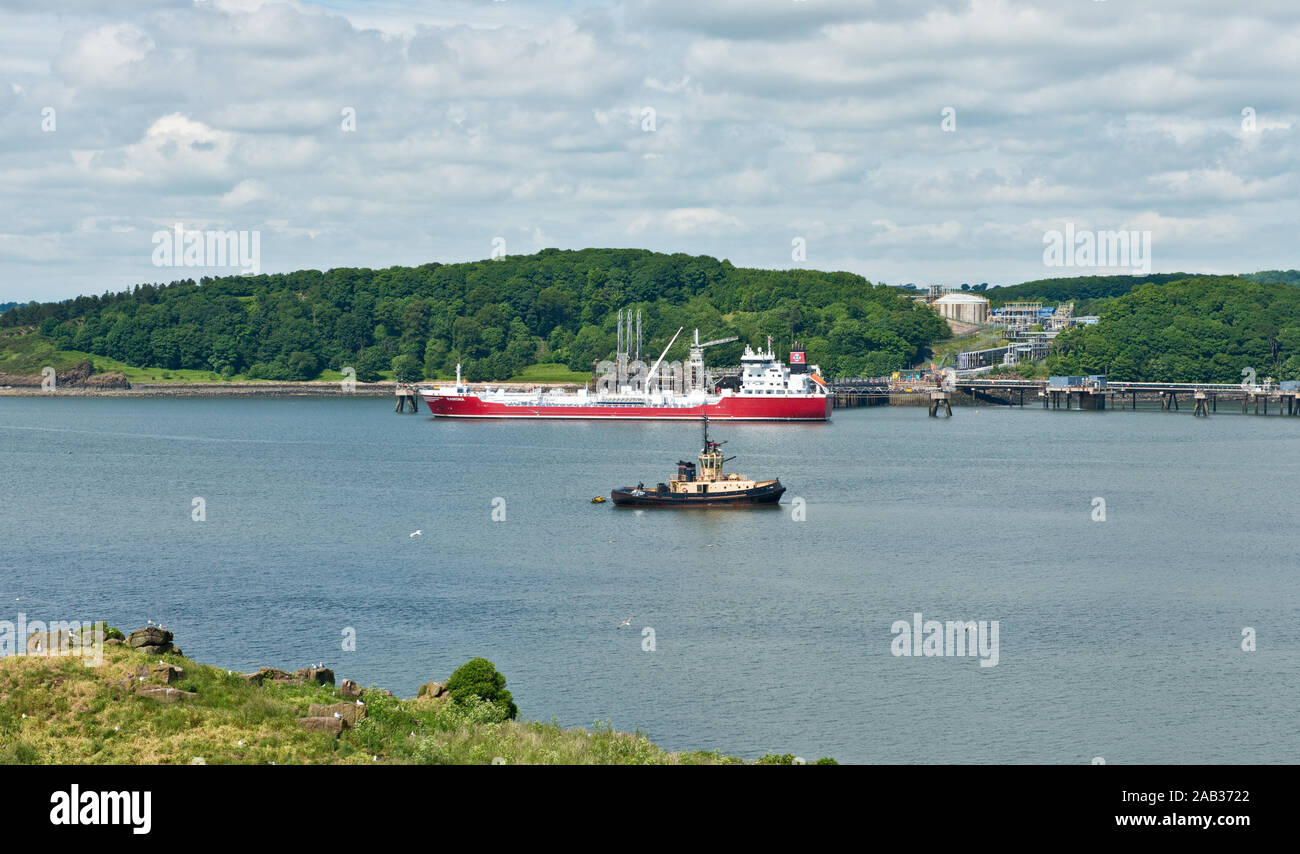 Oil tanker and tug at export terminal on Fife coast. View from Inchcolm Island in Firth of Forth. Scotland Stock Photo