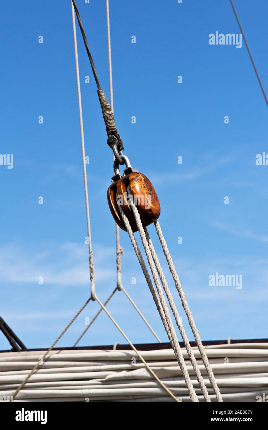 Eine Umlenkrolle aus Holz mit Tauwerk auf einem Traditionssegler |A wooden pulley with ropes on a sailing yacht| Stock Photo