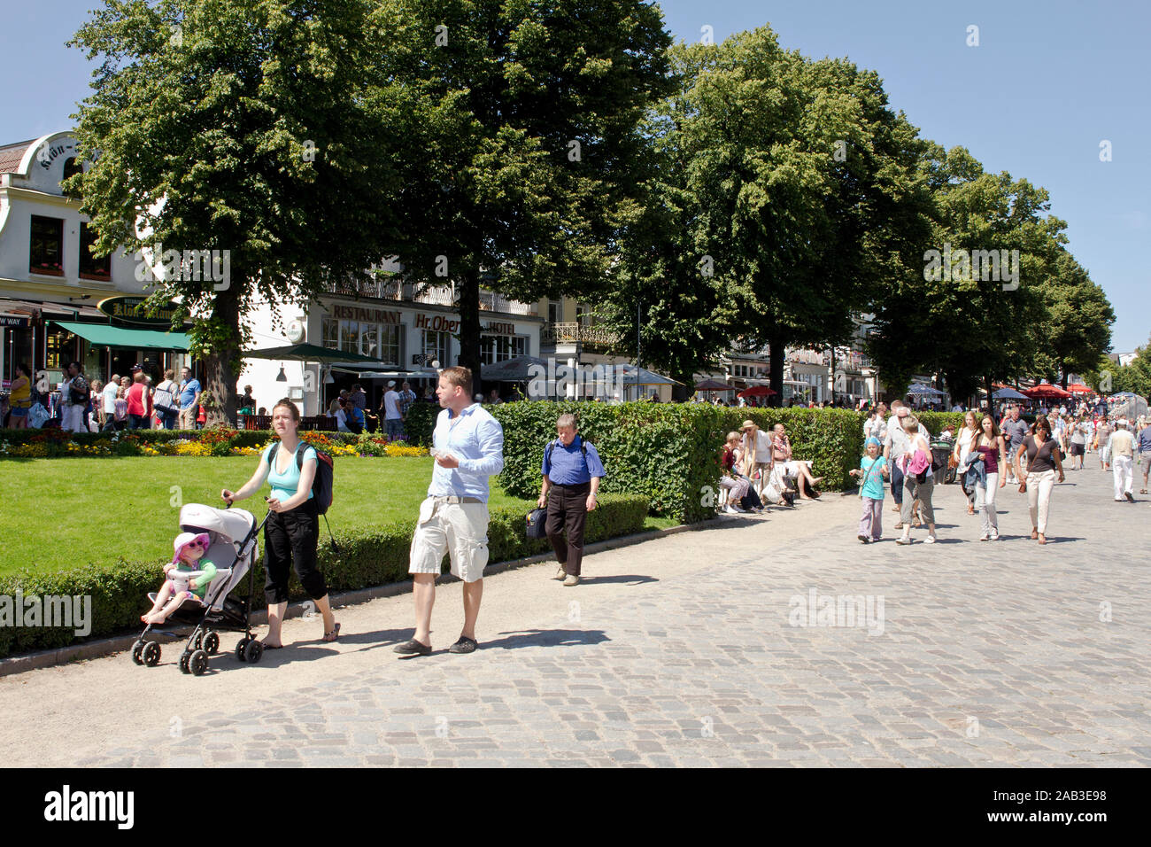 Touristen flanieren über die Promenade in Warnemünde und genießen das sommerliche Wetter |Tourists stroll along the boardwalk in Warnemünde and enjoy Stock Photo