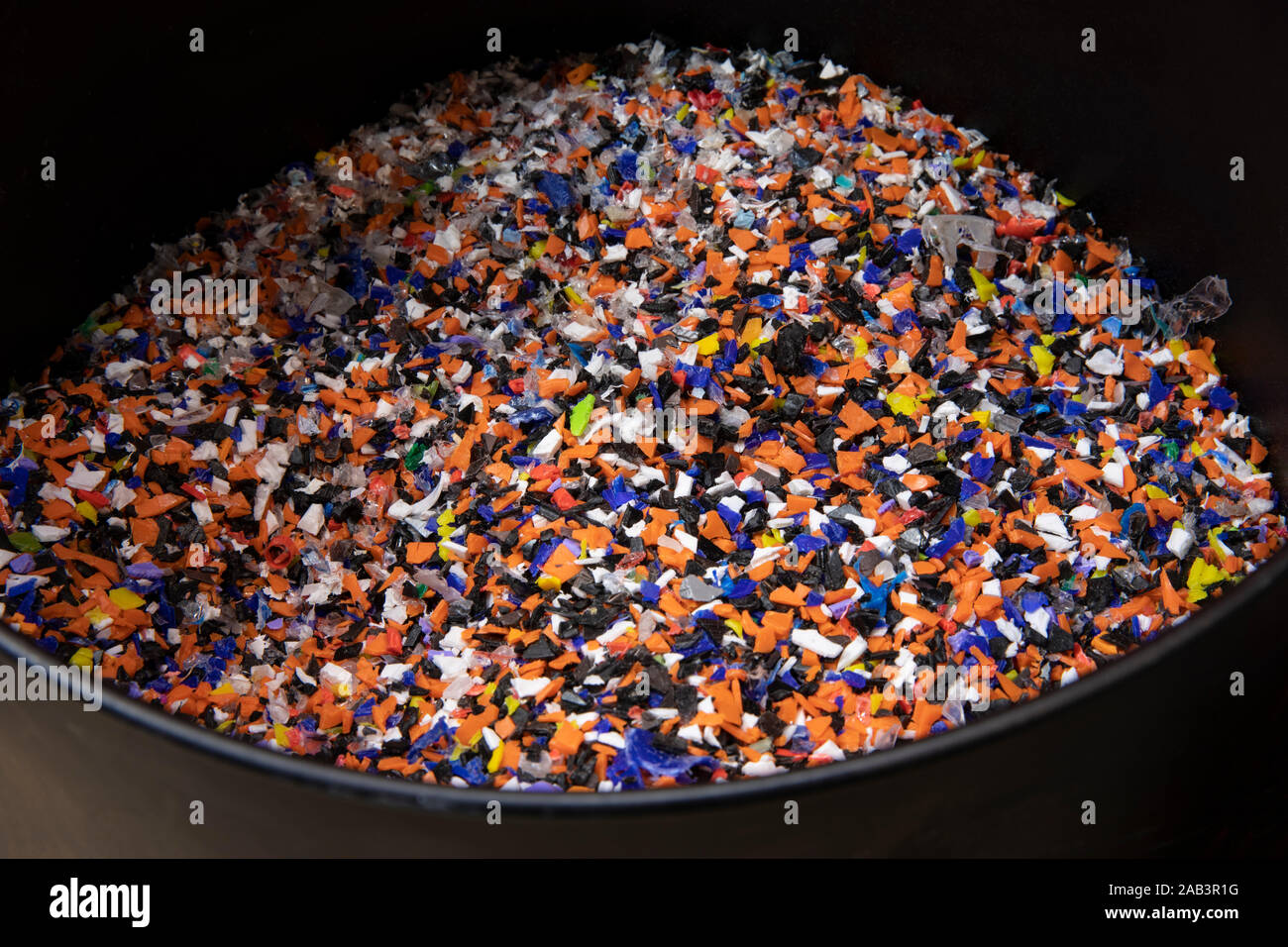 Plastic pellets made of multicolored recylced bottle caps in a black ...