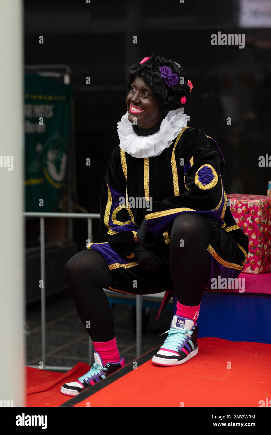 Eindhoven, The Netherlands, November 23rd 2019. Zwarte Piet wearing her colorful costume with golden details and smiling at the small children to welc Stock Photo