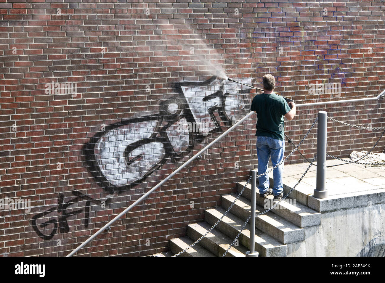 Mann entfernt Graffiti an einer Mauer |Man removed graffiti on a wall| Stock Photo