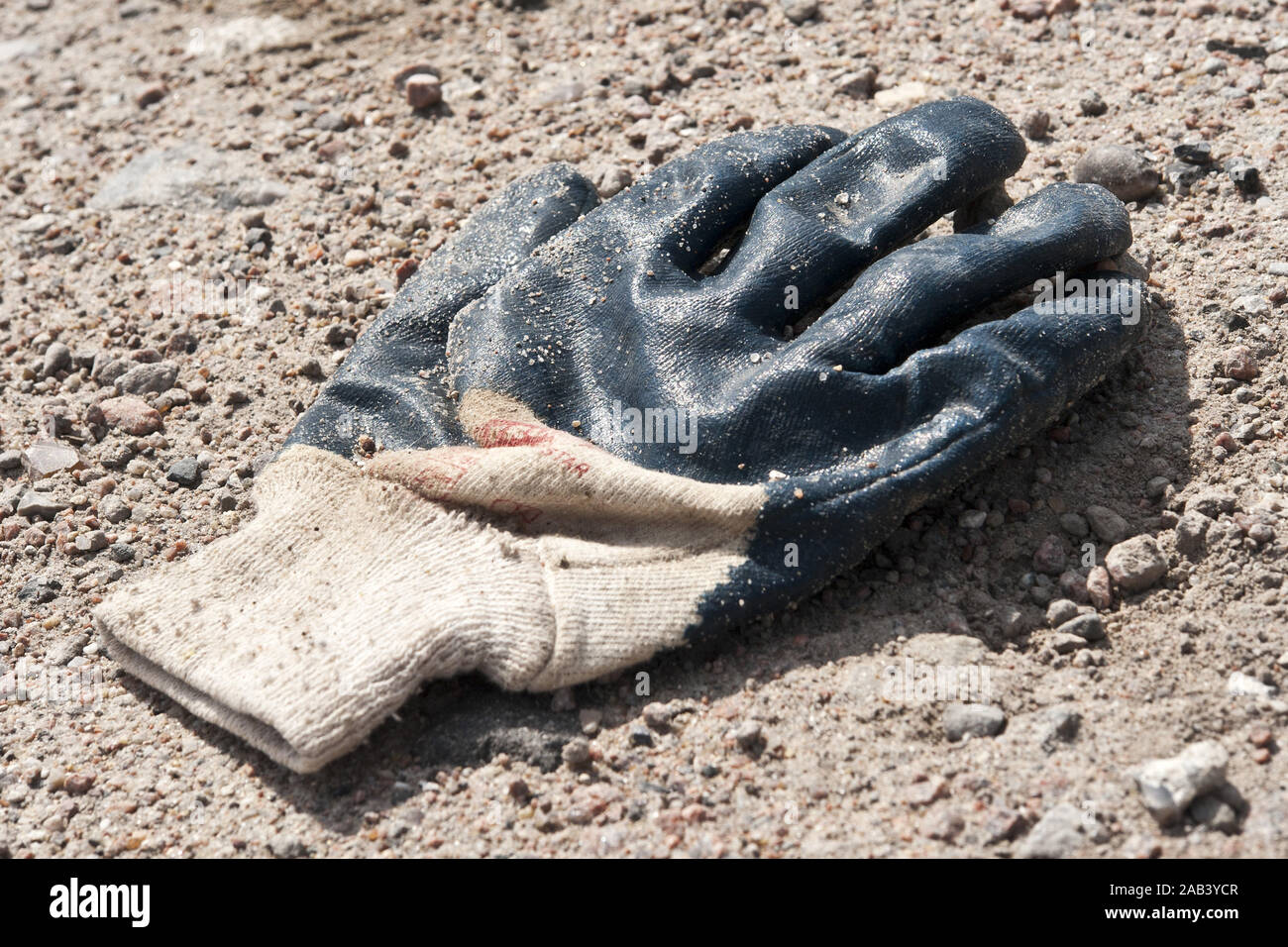 Ein gebrauchter Arbeitshandschuh im Sand |A used work glove in the sand| Stock Photo