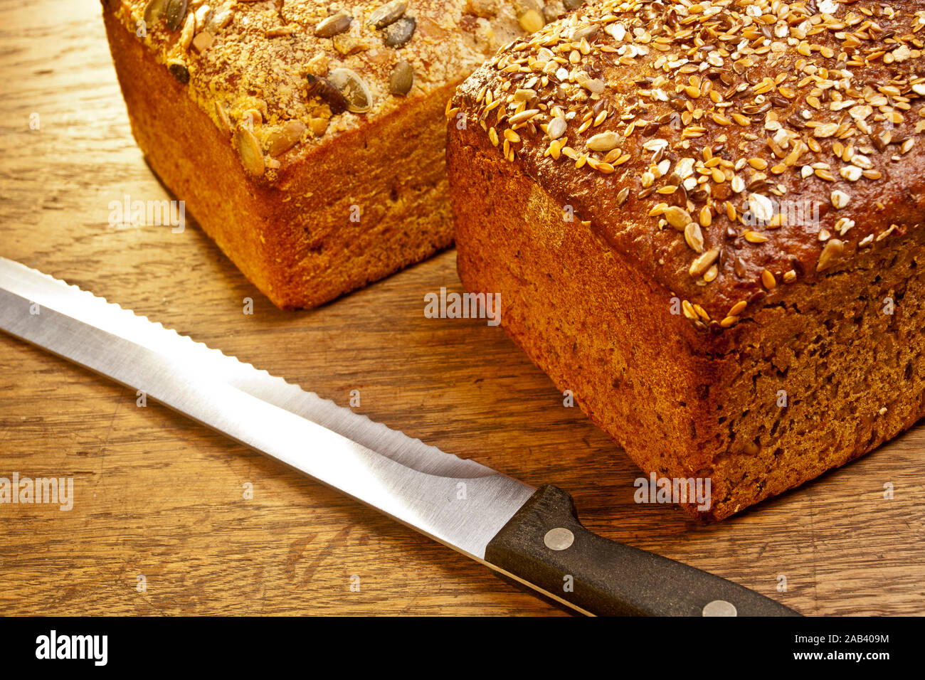 Mehrkornbrot und Kürbiskernbrot mit einem Brotmesser auf einer Tischplatte |Multi-grain bread and pumpkin bread with a bread knife on a table top| Stock Photo