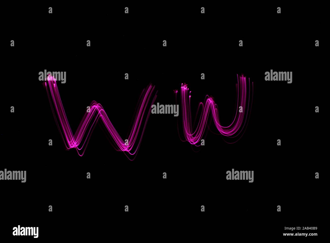 Long exposure photograph of the letter w in pink neon color, in upper case and lower case, parallel lines pattern against a black background. Stock Photo