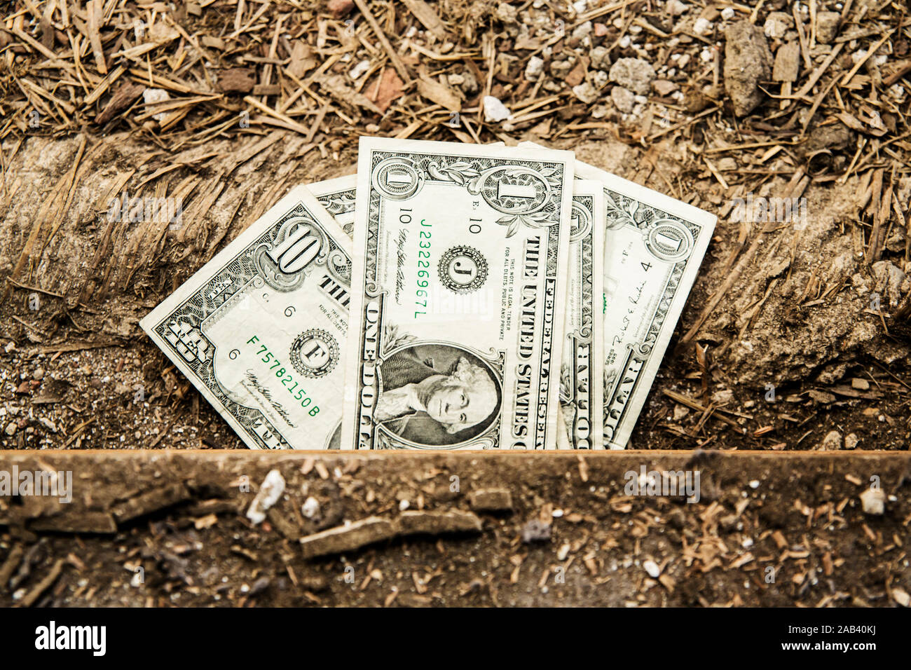 Dollarnoten schauen unter einem aufgerissenen Fußboden hervor |Dollar bills look from beneath a wide-open floor| Stock Photo