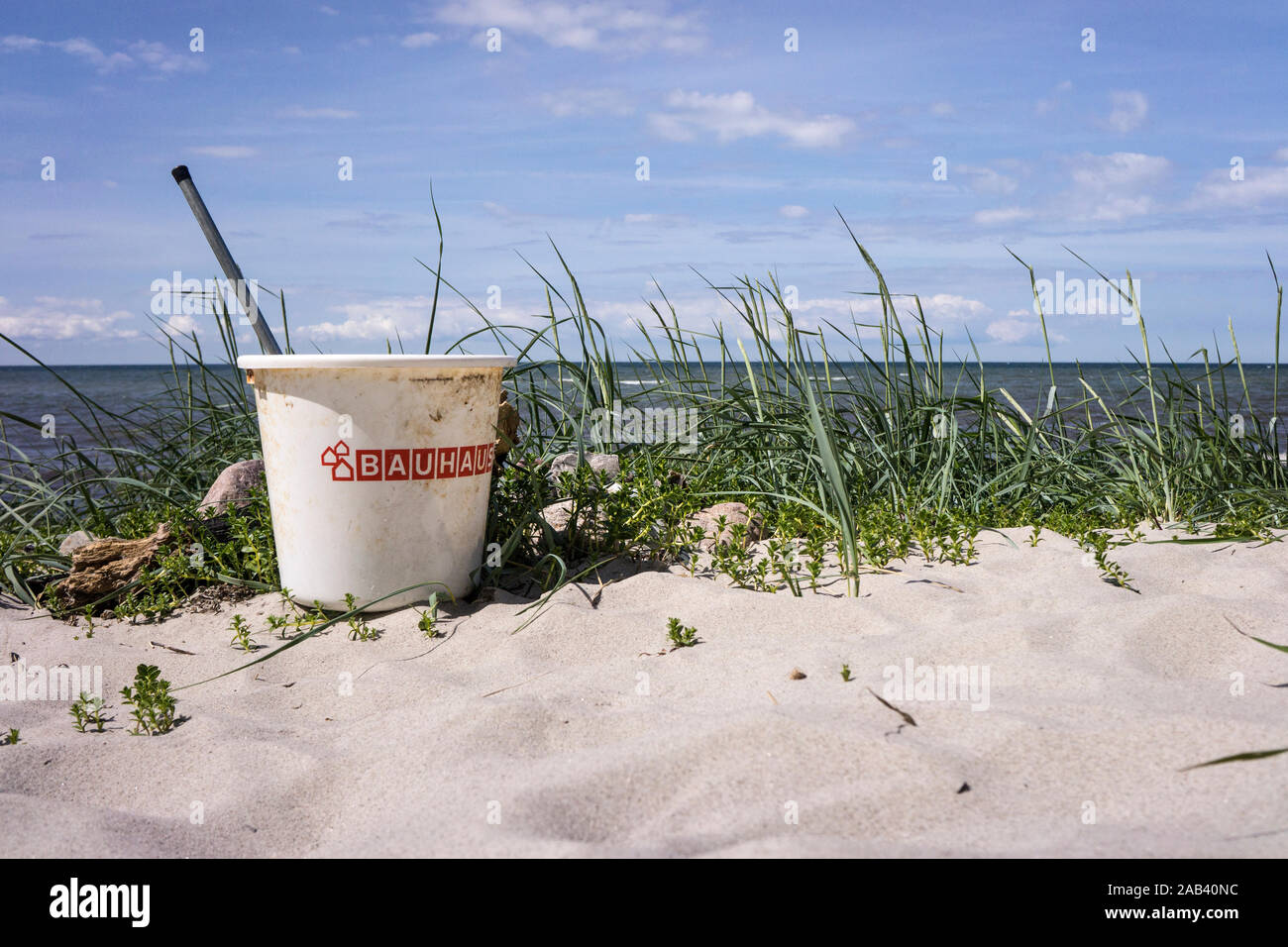 Ein zurückgelassener, mit Unrat gefüllter Plastikeimer vom Bauhaus am Strand |A left behind, filled with plastic trash bucket by Bauhaus on the beach| Stock Photo