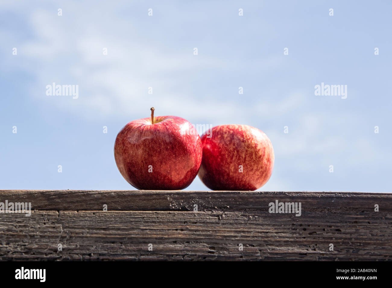 Zwei Äpfel auf einer Kiste vor blauem Himmel |Two apples on a crate in front of blue sky| Stock Photo