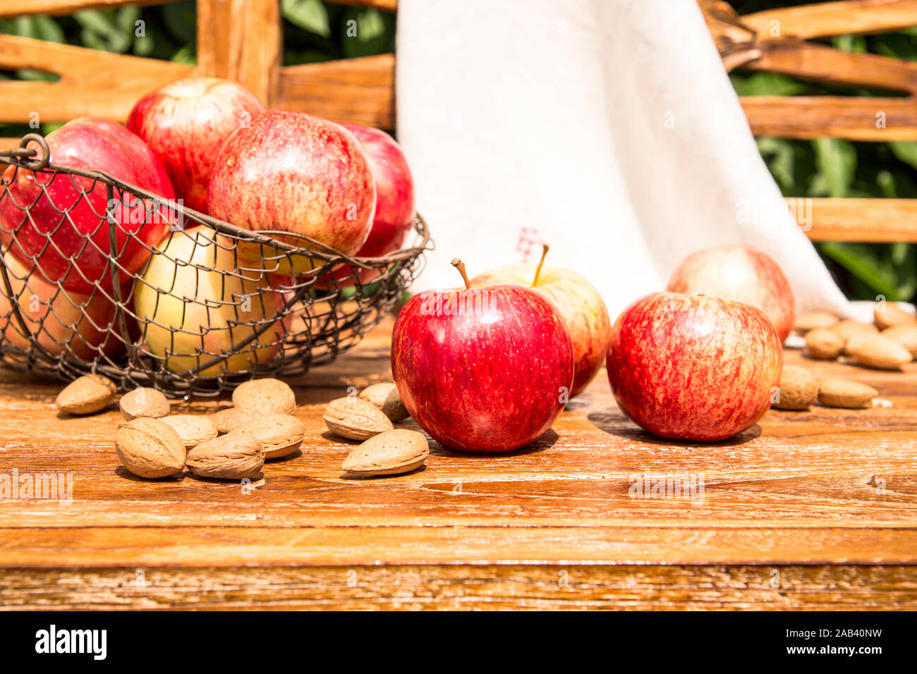 Äpfel und Mandeln liegen zusammen auf einer Holzbank im Garten |Apples and almonds lying together on a wooden bench in the garden| Stock Photo
