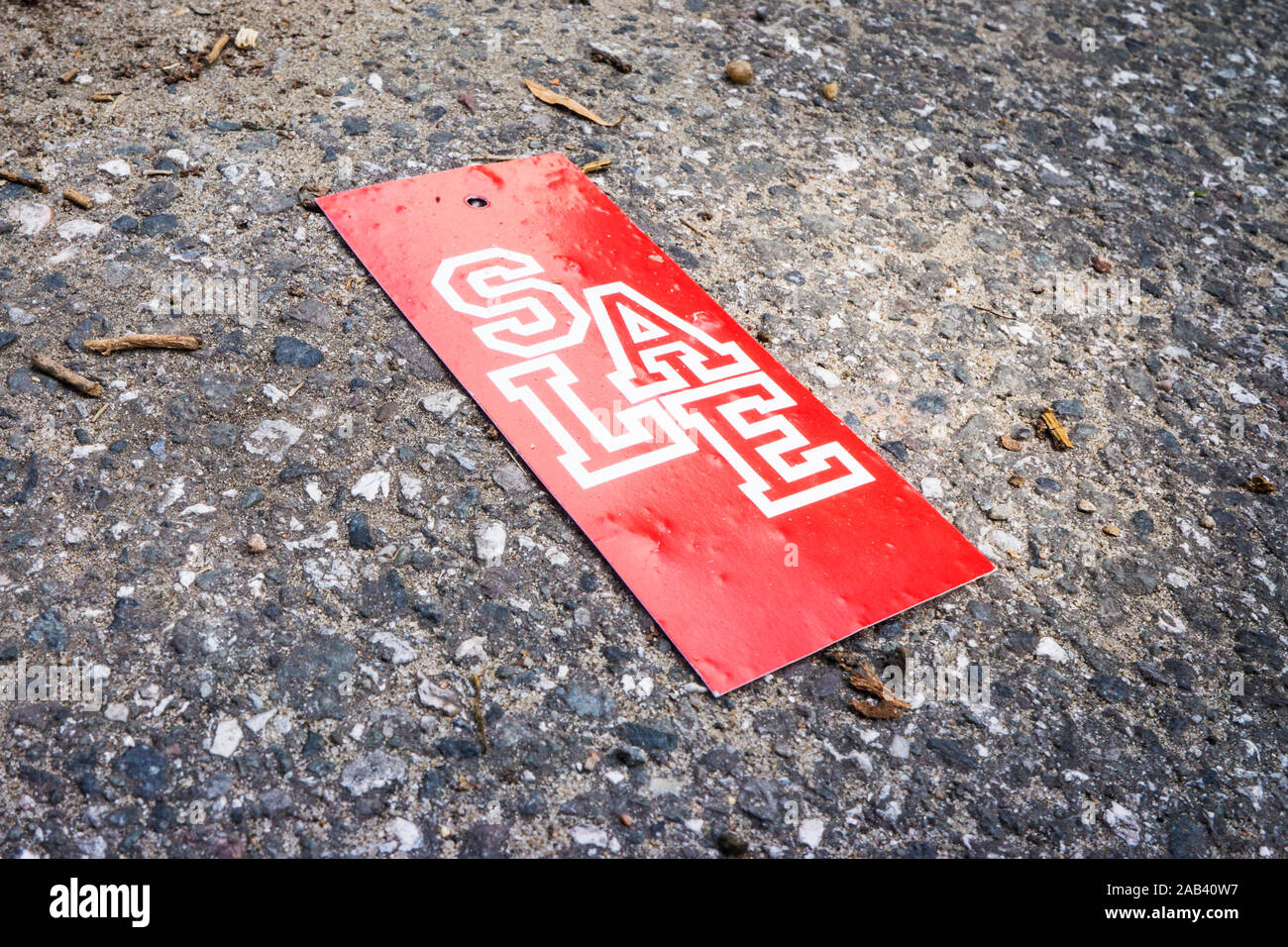 Ein rotes Pappschild mit der Aufschrift „Sale“ liegt auf einer Straße |A red cardboard sign with the word 'Sale' is located on a street| Stock Photo