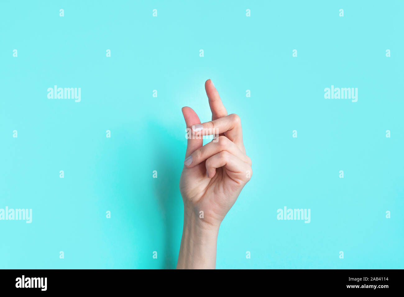 Female snapping hand on blue background, copy space. Fingers snapping. Snap gesture, minimal concept. Stock Photo