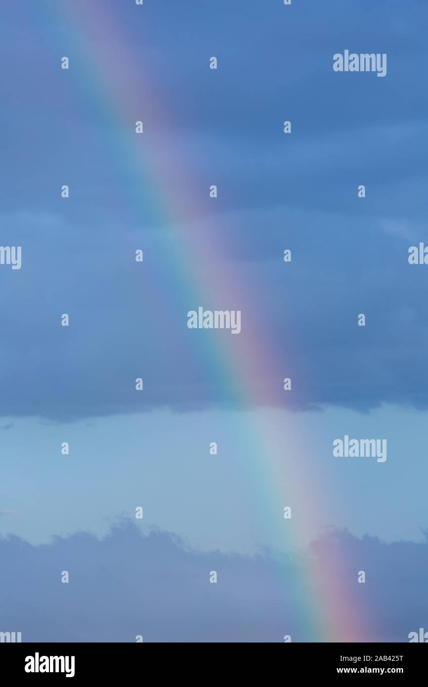 A piece of rainbow in the sky against the background of rain clouds ...
