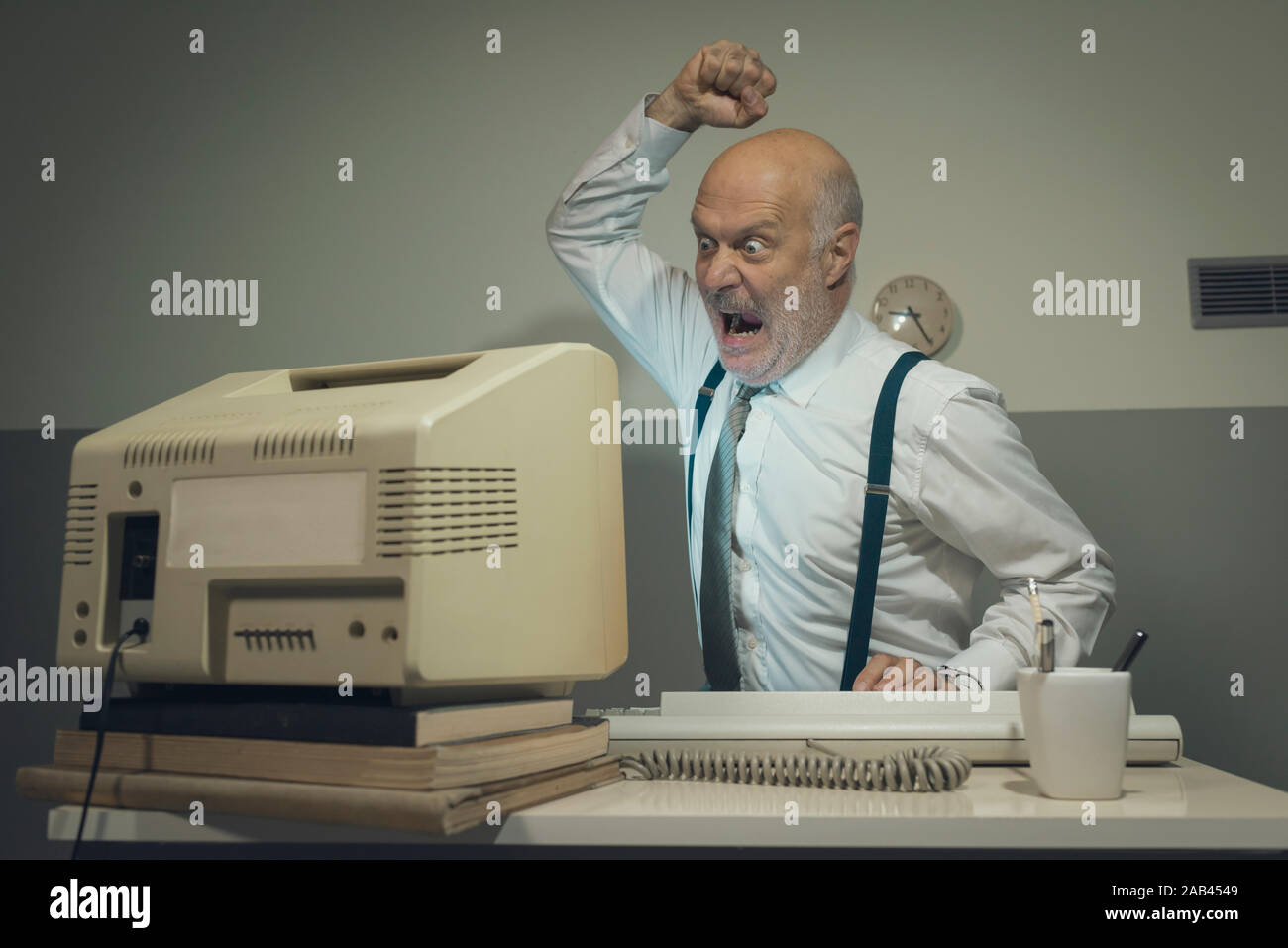 Angry stressed office worker hitting his old broken computer Stock