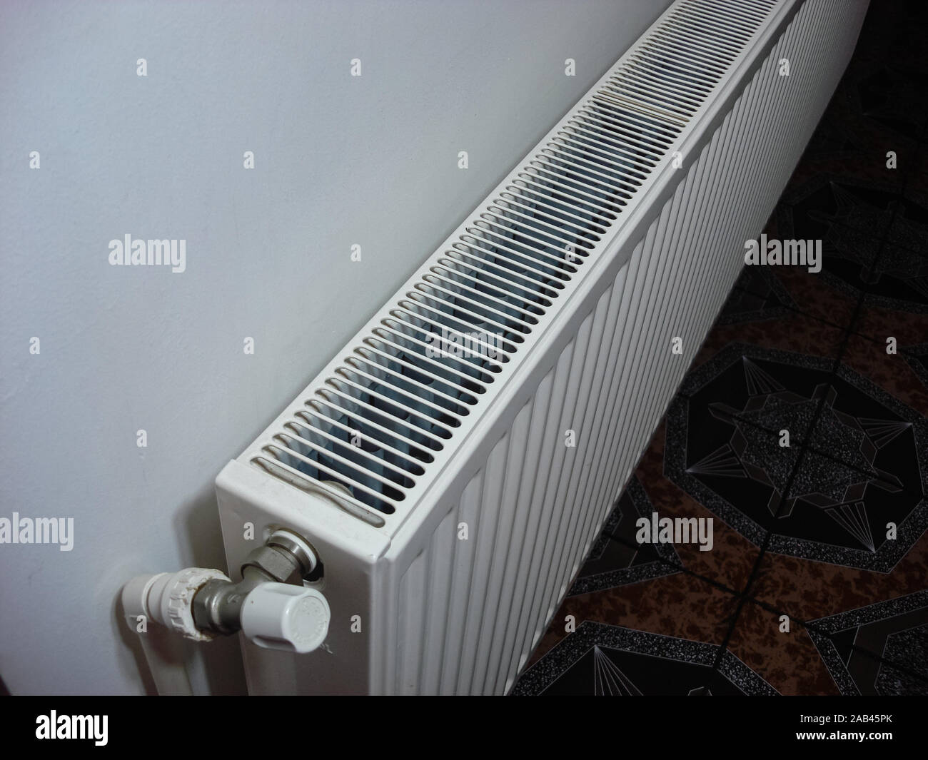 White metal heating radiator mounted on a wall in room interior.  Bucharest, Romania, 2019. Stock Photo
