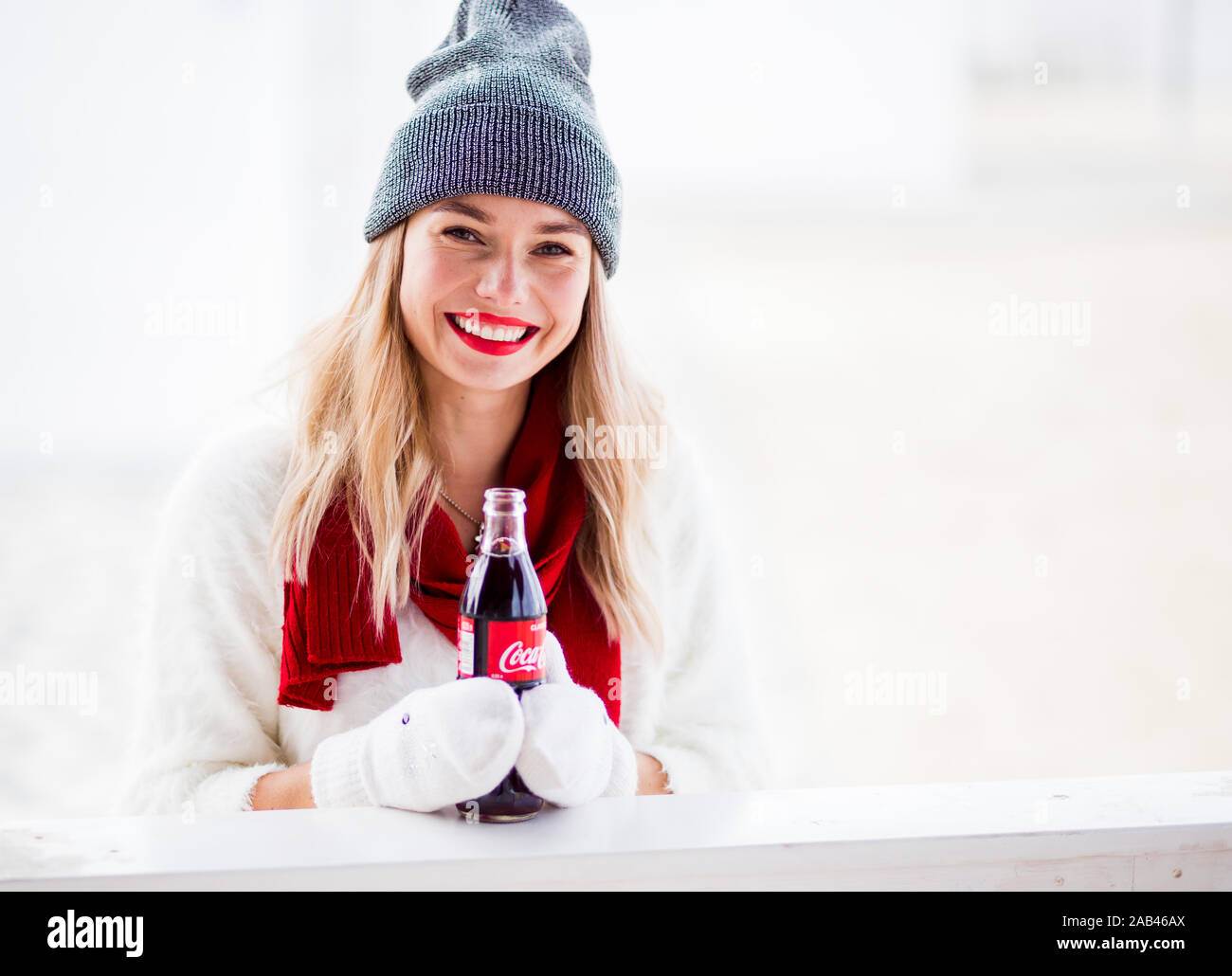 Russia, Sochi - November 23, 2019: Pretty girl holding in hands two coca cola bottles and laughing at Chirstmas day Stock Photo