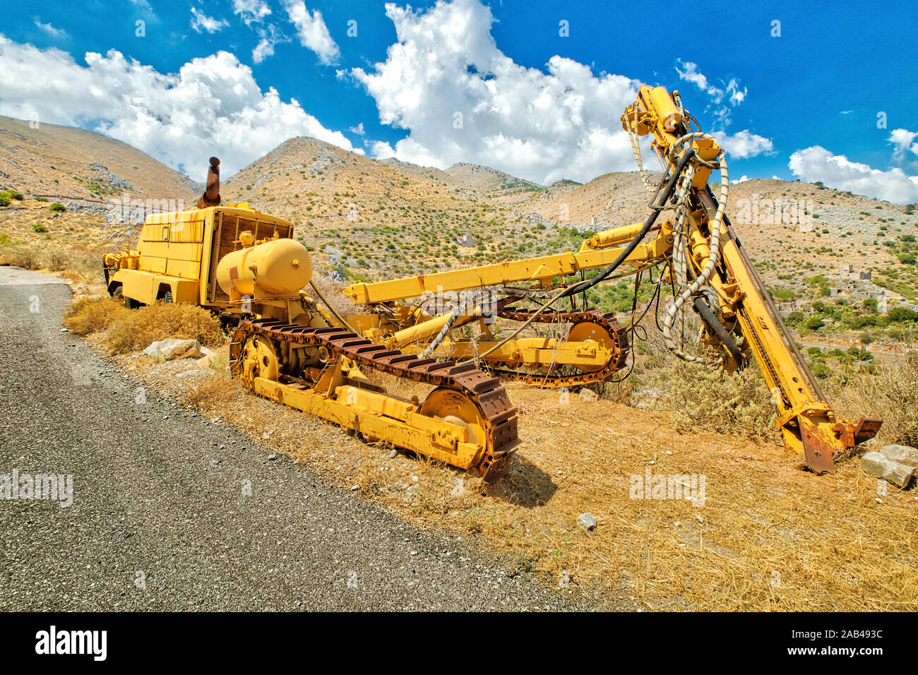 Tracked bulldozer with drilling machine at work along road. Work in progress, industrial machine. Mining landscape on background. Stock Photo