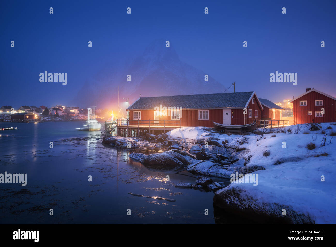 Beautiful norwegian Rorbu on sea cost and snowy mountain at night Stock Photo