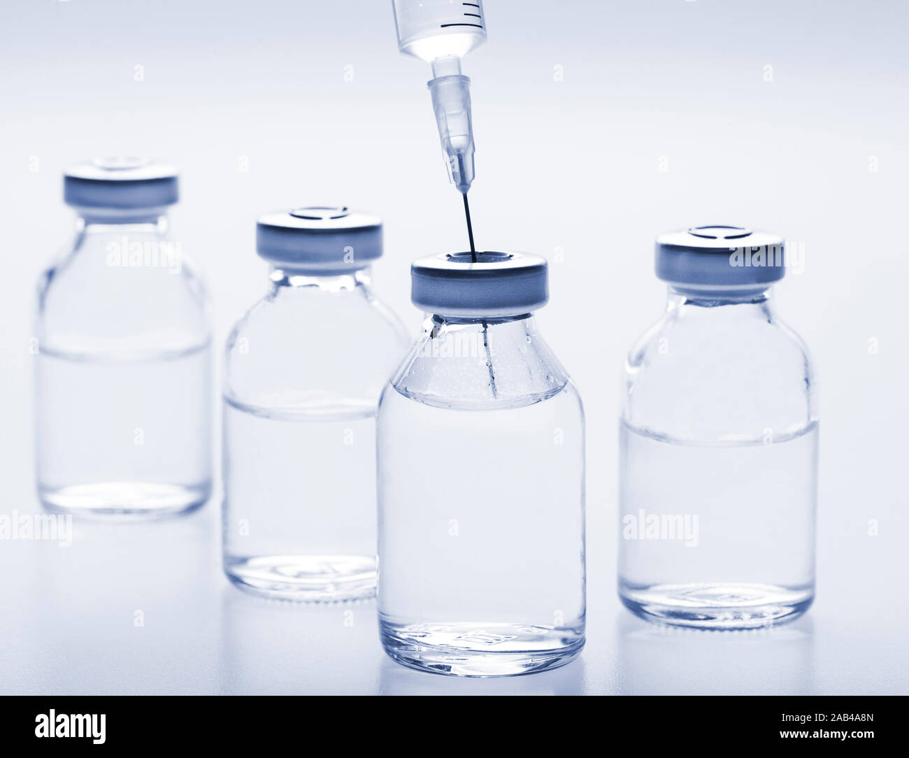 Glass medicine vials with liquid and syringe on white background. Toned ...