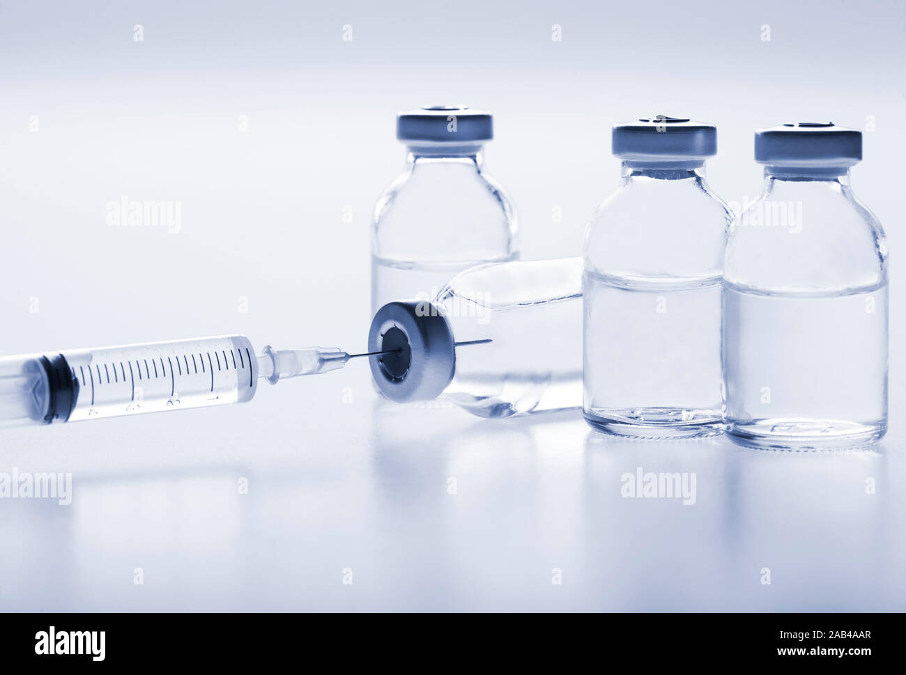 Glass medicine vials with liquid and syringe on white background. Toned ...