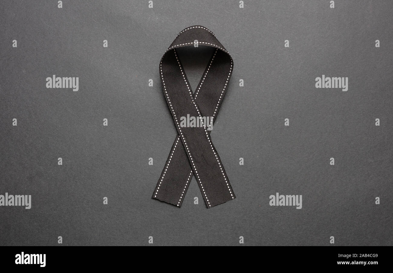 Melanoma awareness ribbon on black color background. Mourning and sorrow symbol. Stock Photo