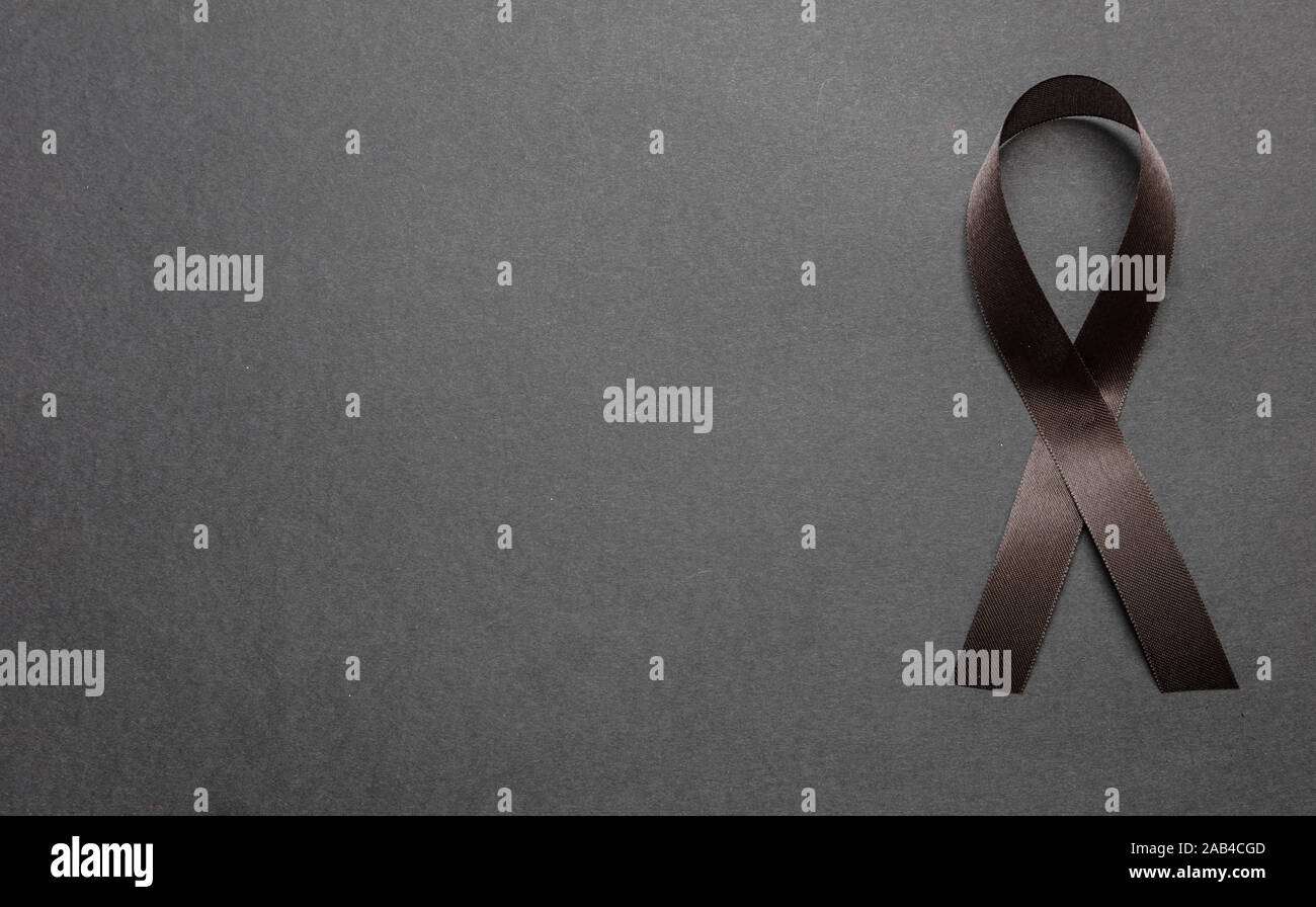 Melanoma awareness ribbon on black color background. Mourning and sorrow symbol. Stock Photo